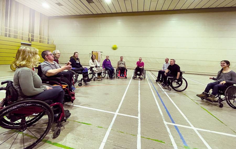 Gruppe von Rollstuhlfahrern im Kreis bei Ballspiel