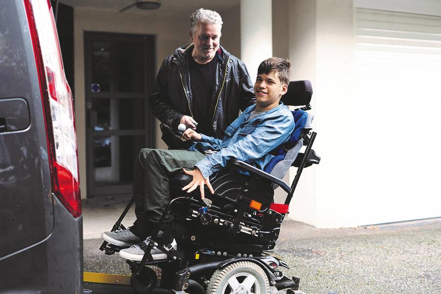 Junge im Rollstuhl auf Laderampe mit Vater