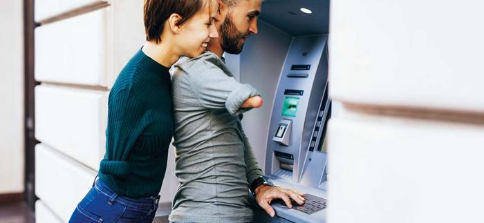 Zwei Menschen ohne rechte Hand stehen am Geldautomat