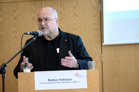 Markus Hofmann am Rednerpult, er ist DGB-Vorsitzender Sozialpolitik und Vorstandsvorsitzender der BAR