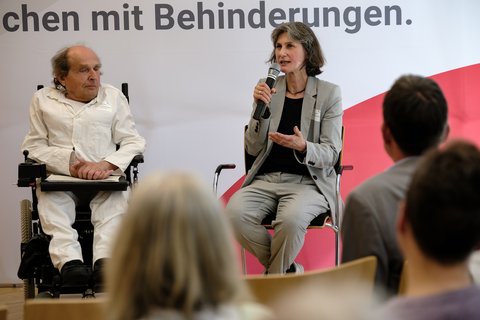 Das Foto zeigt zwei Teilnehmer der erten Podiumsrunde: Podium "Reha & Pflege im Alltag": Uwe Frevert (SLiN e.V., links) und Kerrin Stumpf (Leben mit Behinderung Hamburg e.V., rechts) im Gespräch