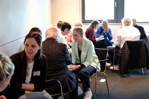 Das Bild zeigt drei Teilnehmer*innen in einem Workshop-Raum gemeinsamen Gespräch.