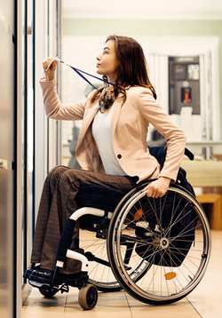 Abbildung einer Rollstuhlfahrerin, die einen Ausweis, den sie an einem BAnd am Hals trägt, hochhält