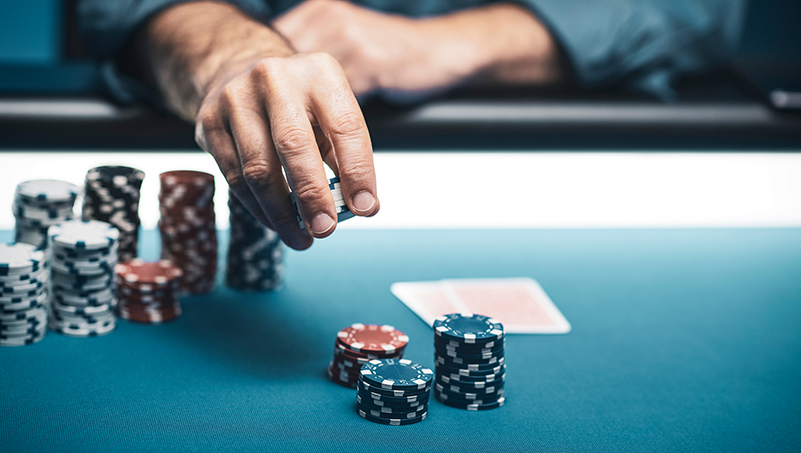 Hand mit Jetons am Spieltisch zwischen Stapeln von Jetons
