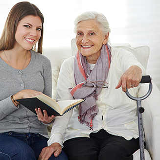 Seniorin auf Sofa neben einer Begleiterin auf dem Sofa sitzen