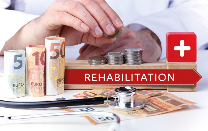 Geldstücke und Noten auf eine Tisch, daneben Hände und ein Schild mit der Aufschrift Rehabilitation